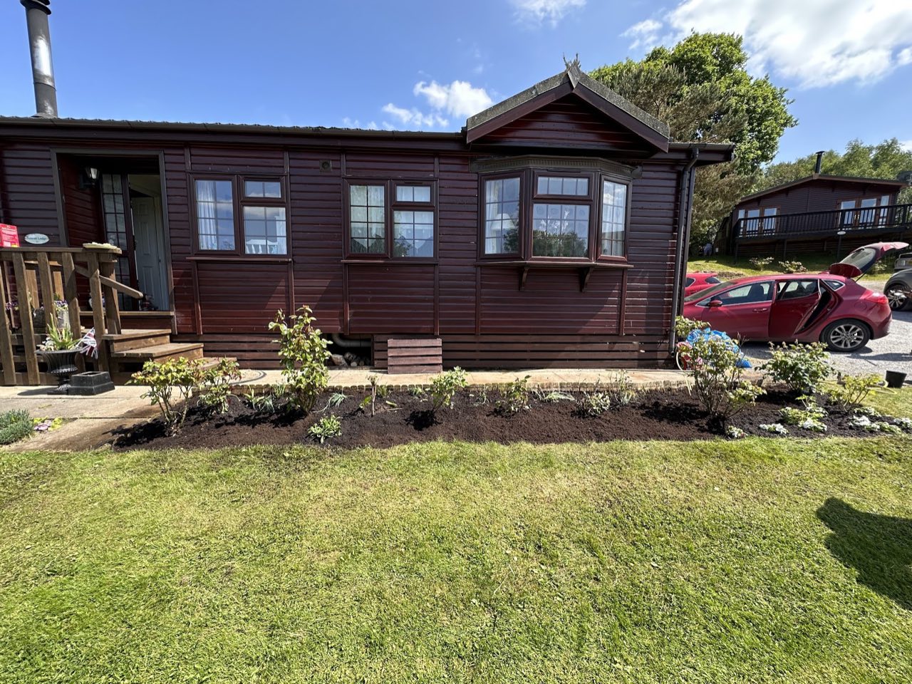 Freshly planted border beds along the front of a timber lodge.