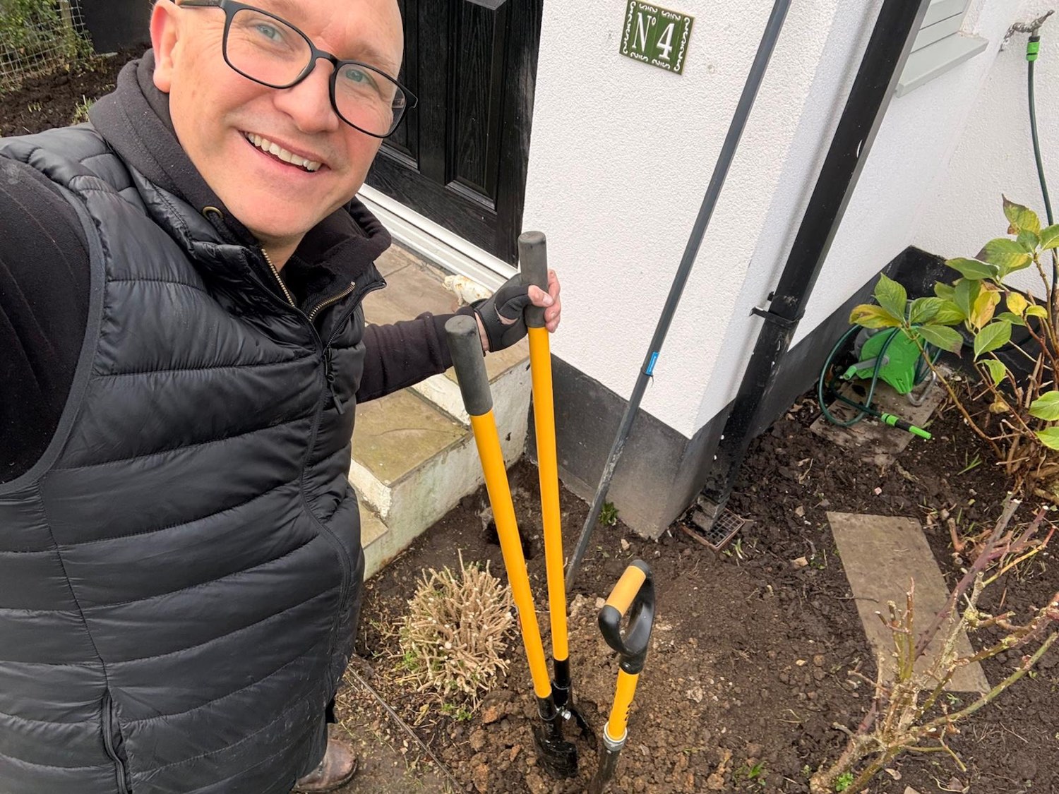 Phil Standen working in a front garden with a pair of post-hole diggers.