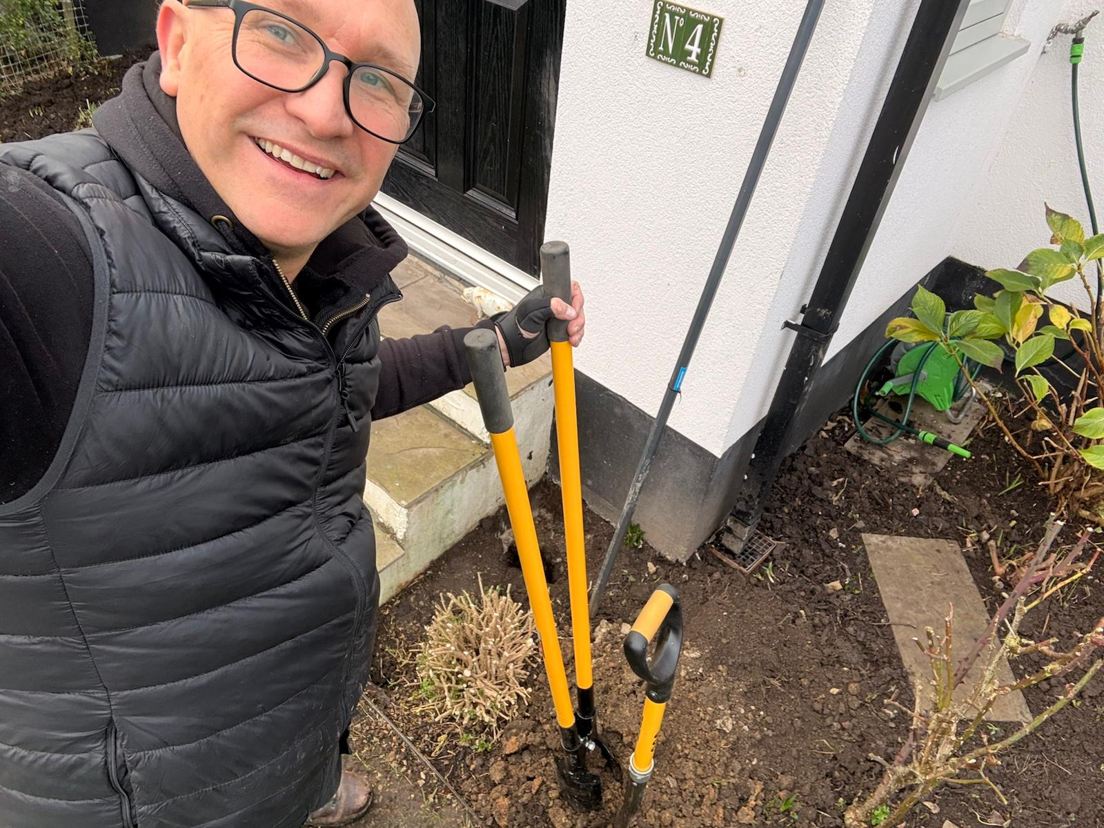 Phil Standen working in a front garden with a pair of post-hole diggers.